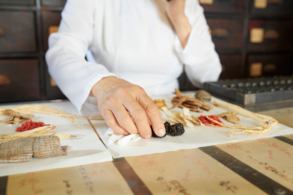 Chinese pharmacy worker choosing dry berries and mushrooms